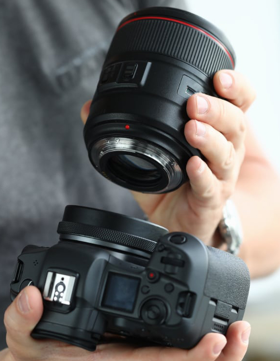 Hands putting on modern digital camera professional lens